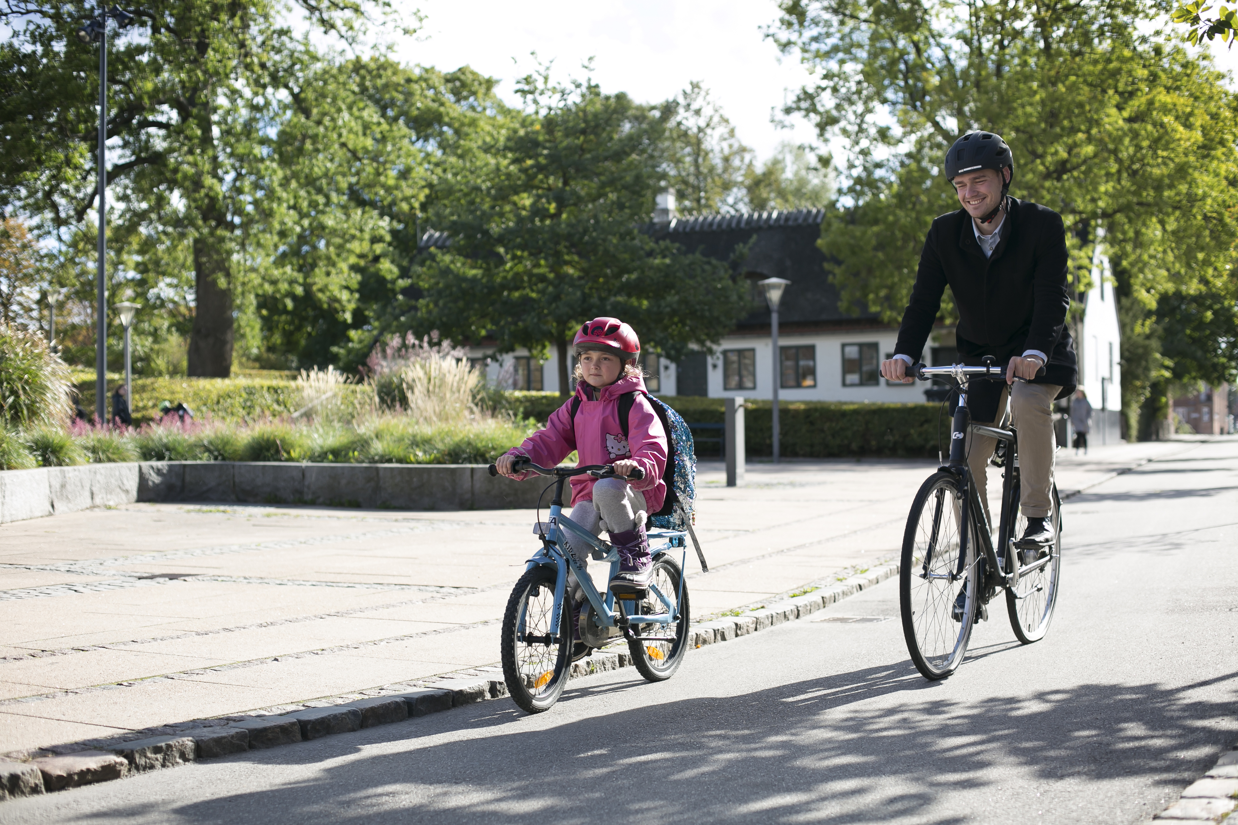 En pige og sin far cykler på vejen