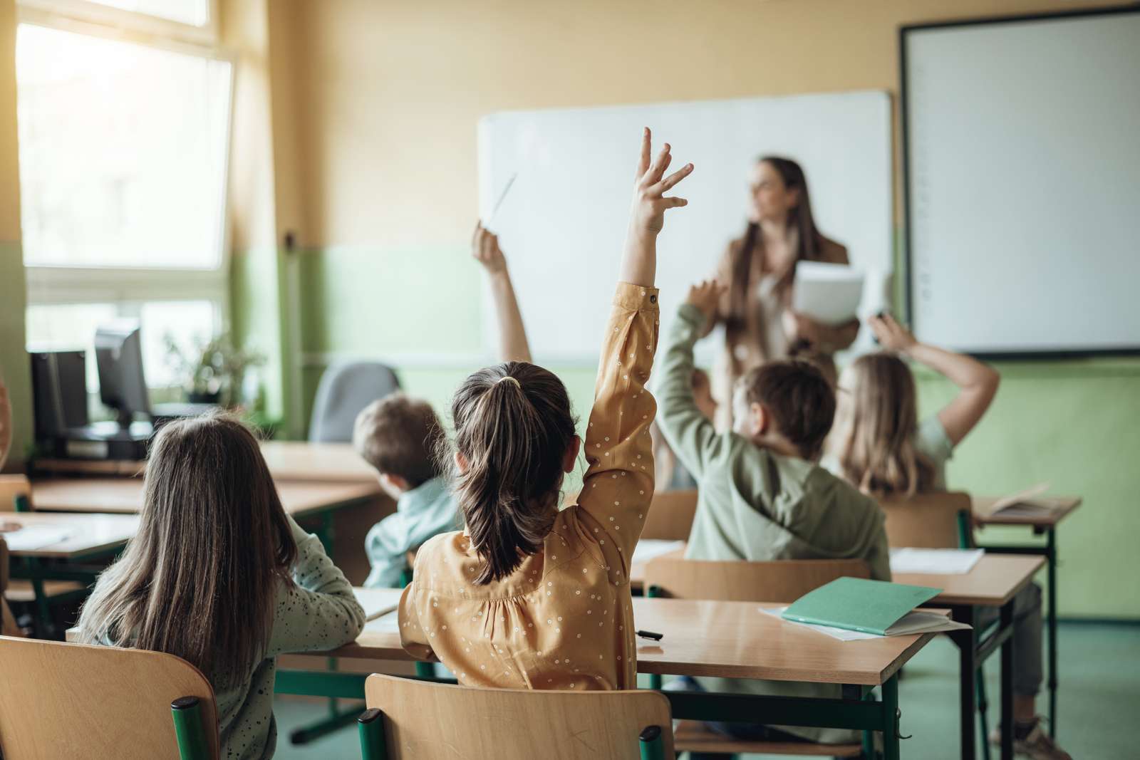 Unge skoleelever rækker hånden op i et klasseværelse