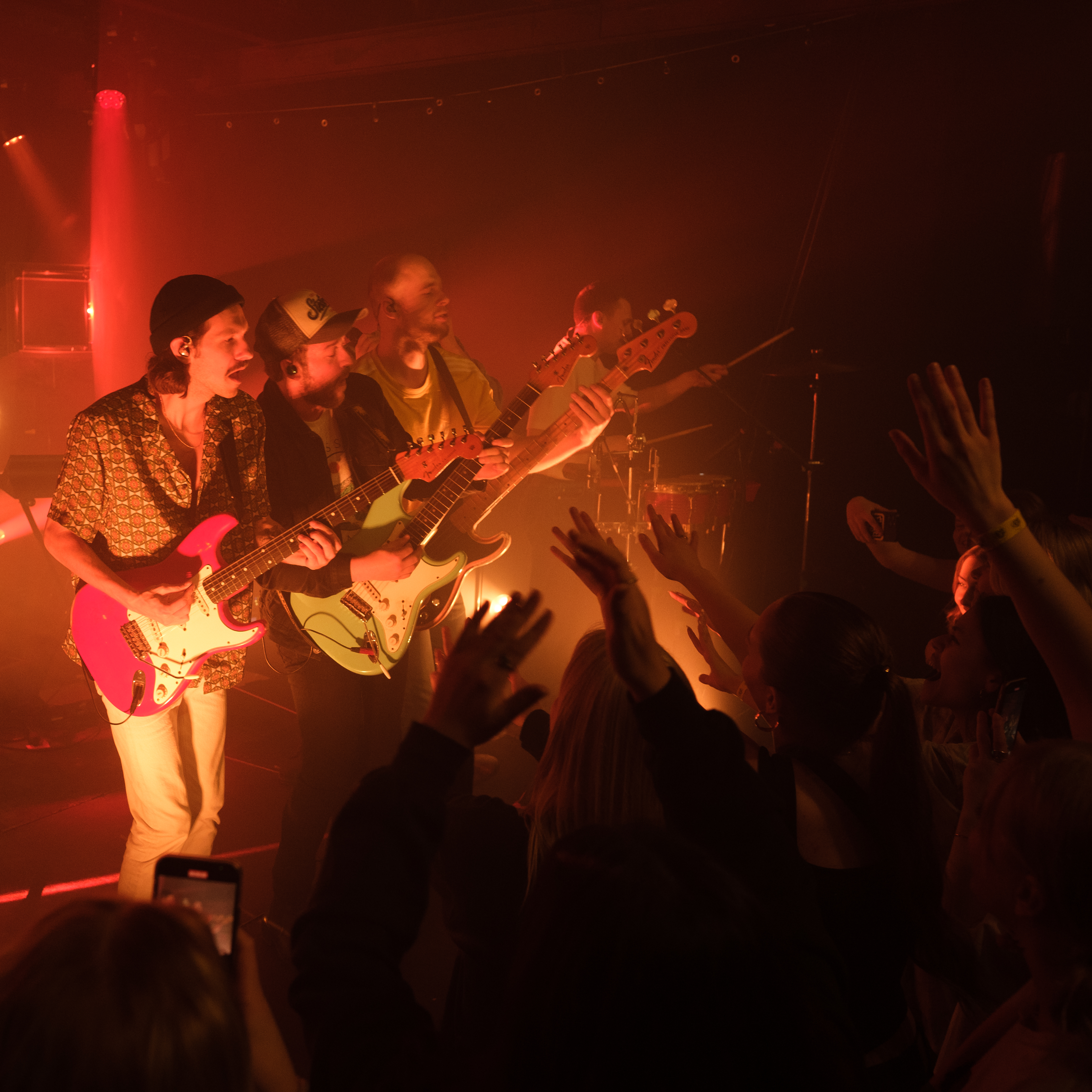 Et band spiller musik på scenen foran et begejstret publikum.